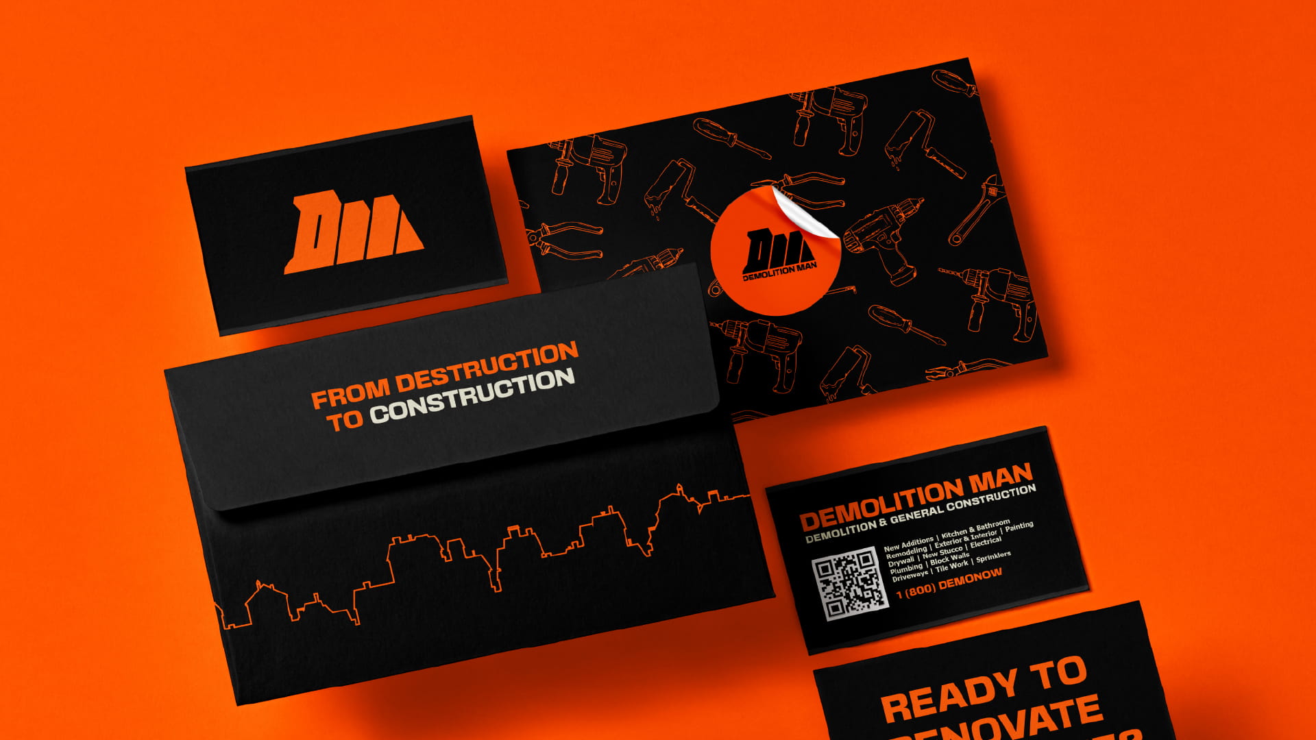 Bold brand identity for Demolition Man, a construction company, featuring black and orange business cards, envelopes, and sticker designs with tool illustrations.